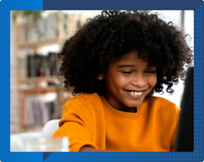 A young child smiling at a computer