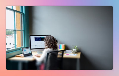 A woman sitting at a desk with two laptops