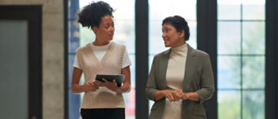 A person holding a tablet and talking to another person.