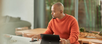 A man looking at the mobile screen while holding tablet on the other hand