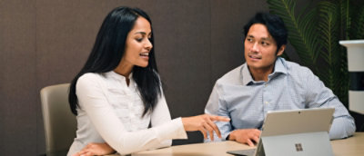 A woman explaining while pointing at the screen to a man