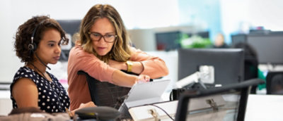 A woman wearing glasses sitting beside a woman and looking at the screen