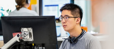 A man wearing glasses looking at the desktop