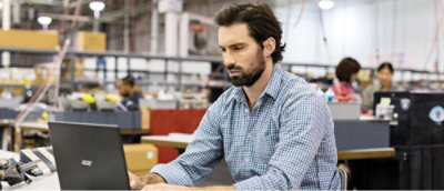Une personne assise à un bureau et utilisant un ordinateur portable.