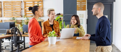 Un grupo de personas trabajando en equipo alrededor de un portátil en un espacio de trabajo de oficina moderno.