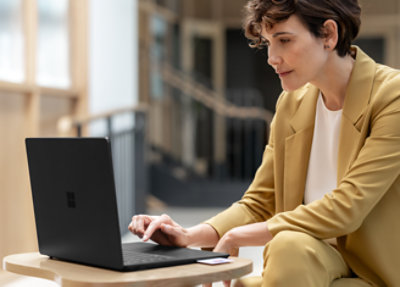 Seorang wanita sedang bekerja menggunakan Microsoft Surface Laptop 4