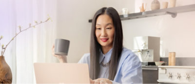  Eine Frau mit langen Haaren, die an einem Schreibtisch mit einem Laptop und einer Tasse sitzt.