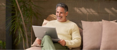 Ein Mann, der auf einer Couch sitzt und einen Laptop hält.