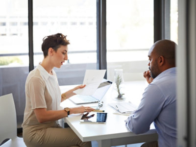 Um homem e uma mulher sentados numa mesa com papéis.