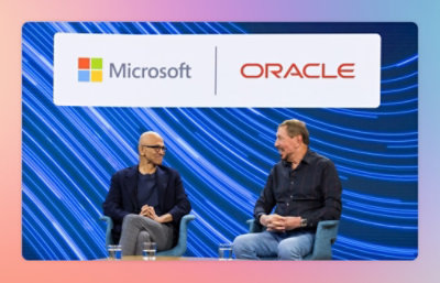 Due uomini che seduti che parlano su un palco davanti a uno sfondo che mostra i logo Microsoft e Oracle