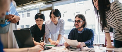 A group of people working together on a table with their laptops.