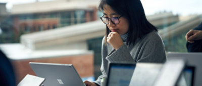 Seseorang sedang melihat laptop dengan satu tangan di dagunya.