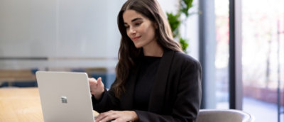 Uma mulher de terno preto olhando para um laptop.