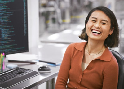 Um close de uma mulher rindo na frente de um computador.