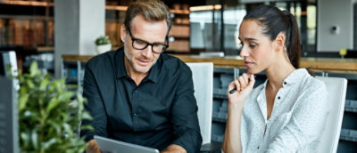 Um homem e uma mulher olhando para um tablet.