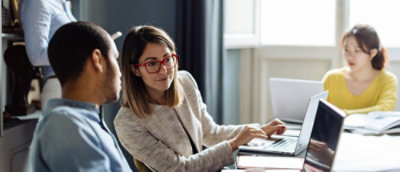 Um homem e uma mulher olhando para um laptop.