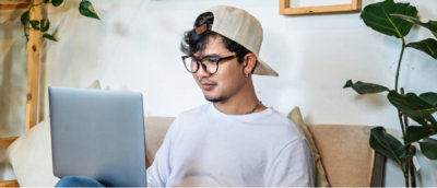 戴眼鏡看著膝上型電腦的男人。