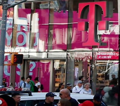큰 자홍색 로고가 있는 T-Mobile 매장 외부에 모인 사람들.