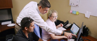 A group of people looking at the laptop.