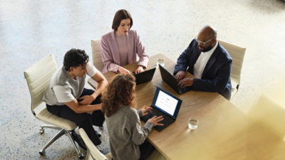  Collaboration en équipe autour d’une table à l’aide d’ordinateurs portables pendant une discussion professionnelle.