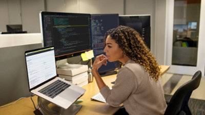 En kvinde, der sidder ved et skrivebord og kigger på en computerskærm.
