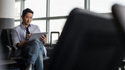 Une personne assise dans un aéroport et utilisant un stylet et une tablette