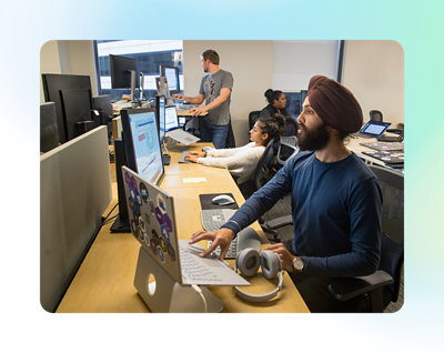 Fyra personer som arbetar vid datorbord på ett kontor, var och en fokuserar på sina skärmar.