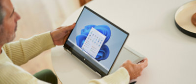 A man sitting at a table using a laptop computer
