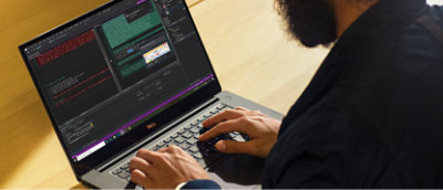 Person som skriver på en bärbar Dell-dator med kodningsprogram öppet, som visar rader med kod och olika programmeringsverktyg 