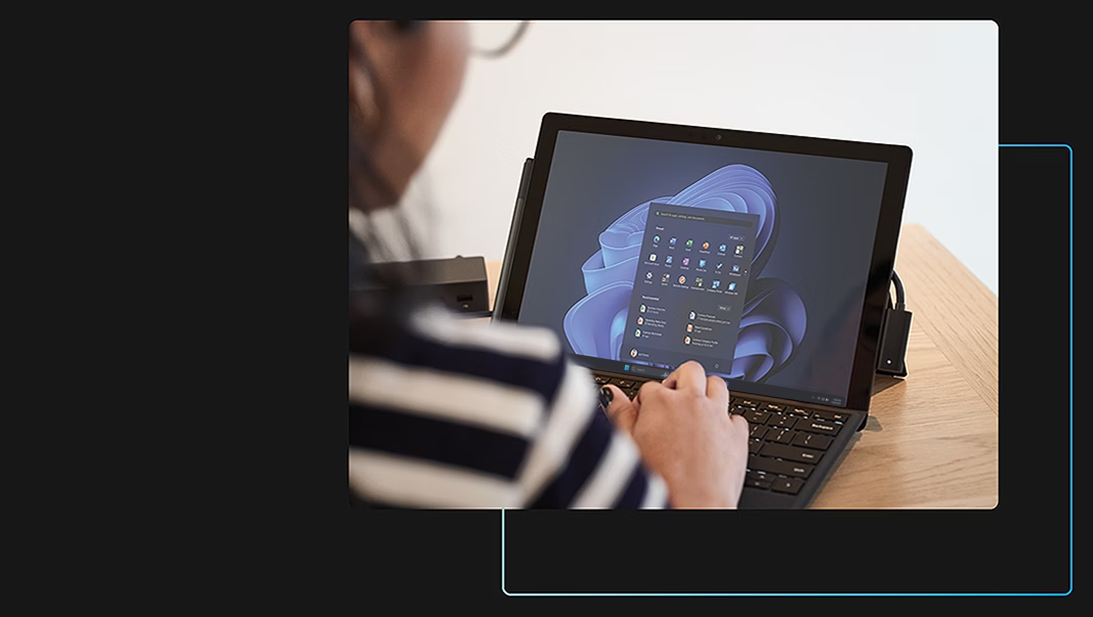 Woman over the shoulder working on laptop with start screen.