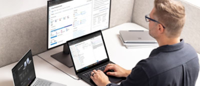Osoba sedící u stolu používá notebook s viditelnou obrazovkou.