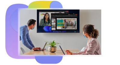 Two people in a conference room wearing PPE while participating in a Teams video call being displayed on a large television.