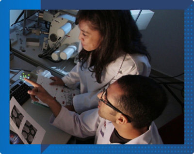Two individuals in lab coats using scientific equipment in a laboratory setting.