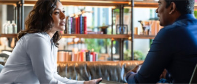 Dos personas conversan en una biblioteca