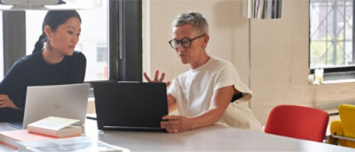 dua orang profesional berbicara sambil bekerja di laptop.