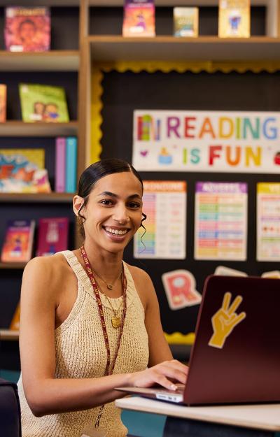 teacher in a school library near a sign stating reading is fun