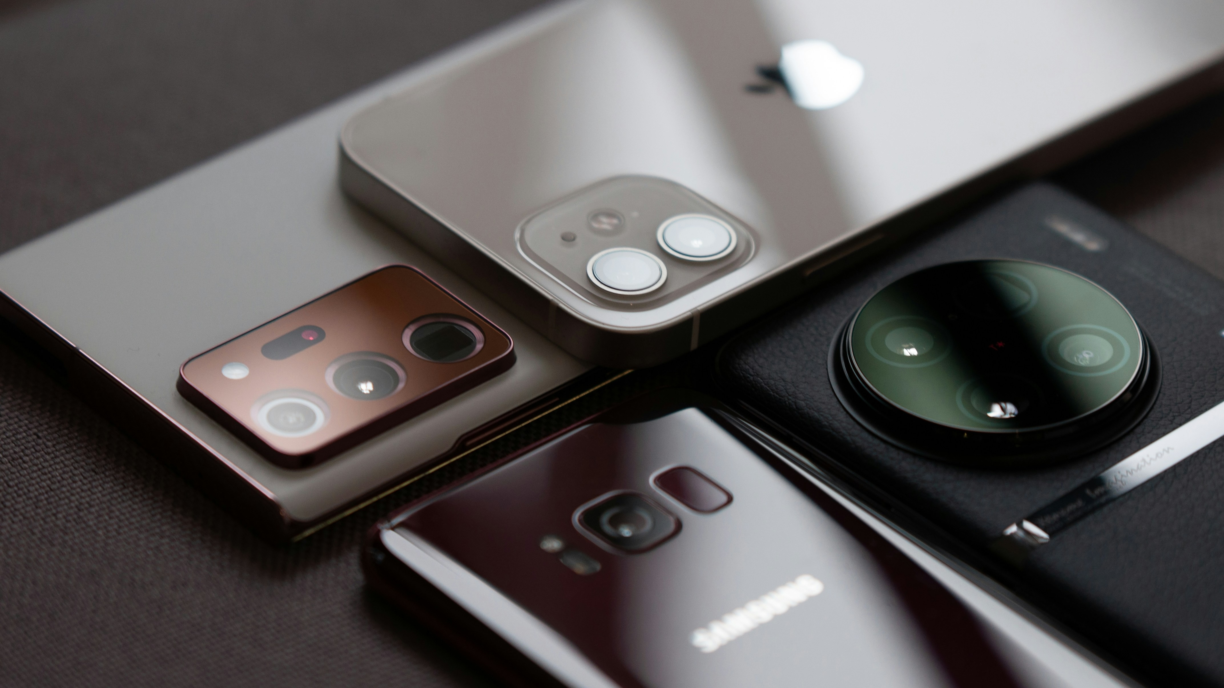 Four grey smartphones on a flat surface
