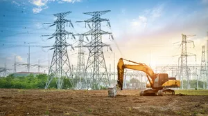 Excavator on the construction site with electric piles and substation in the distance Excavator on the construction site with electric piles and substation in the distance