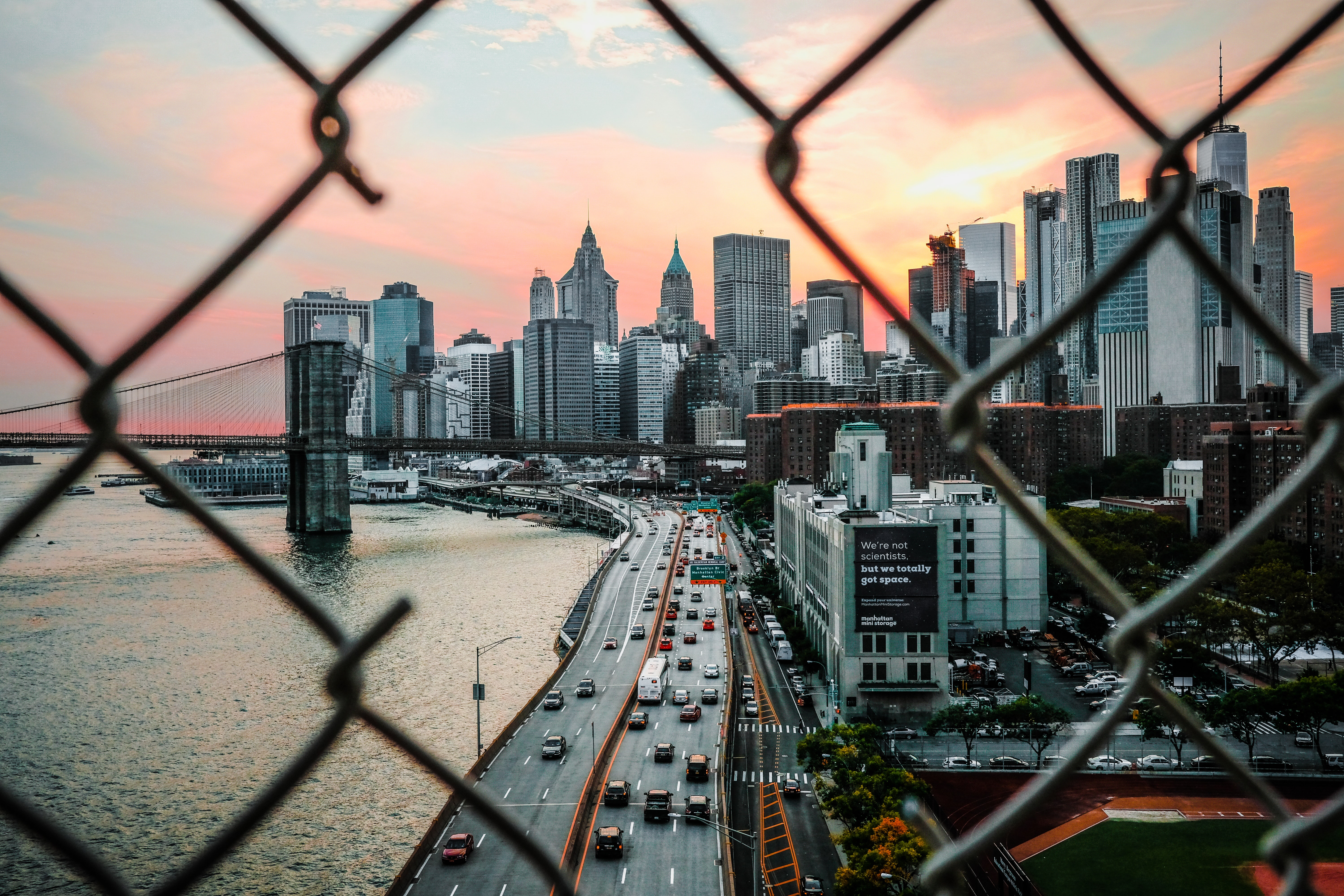 city skyline near bridge and body of water from a view of a broken fence