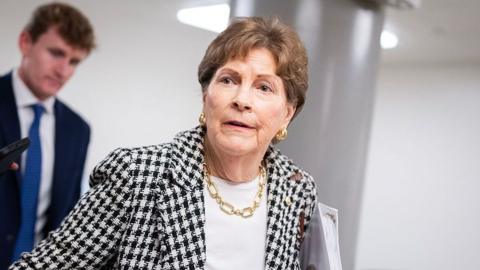 Sen. Jeanne Shaheen, who has short brown hair and is wearing a blazer with a black and white dogtooth pattern, a white top and gold jewellery, talks with reporters during votes in the US Capitol on Wednesday, September 30, 2026.