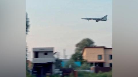 Blurred image of an aircraft in clear skies over two homes