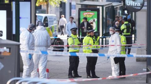 A group of uniformed police officers standing next to forensic officers