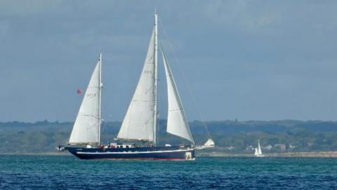A large blue sailing boat on the Solent with three triangular sails