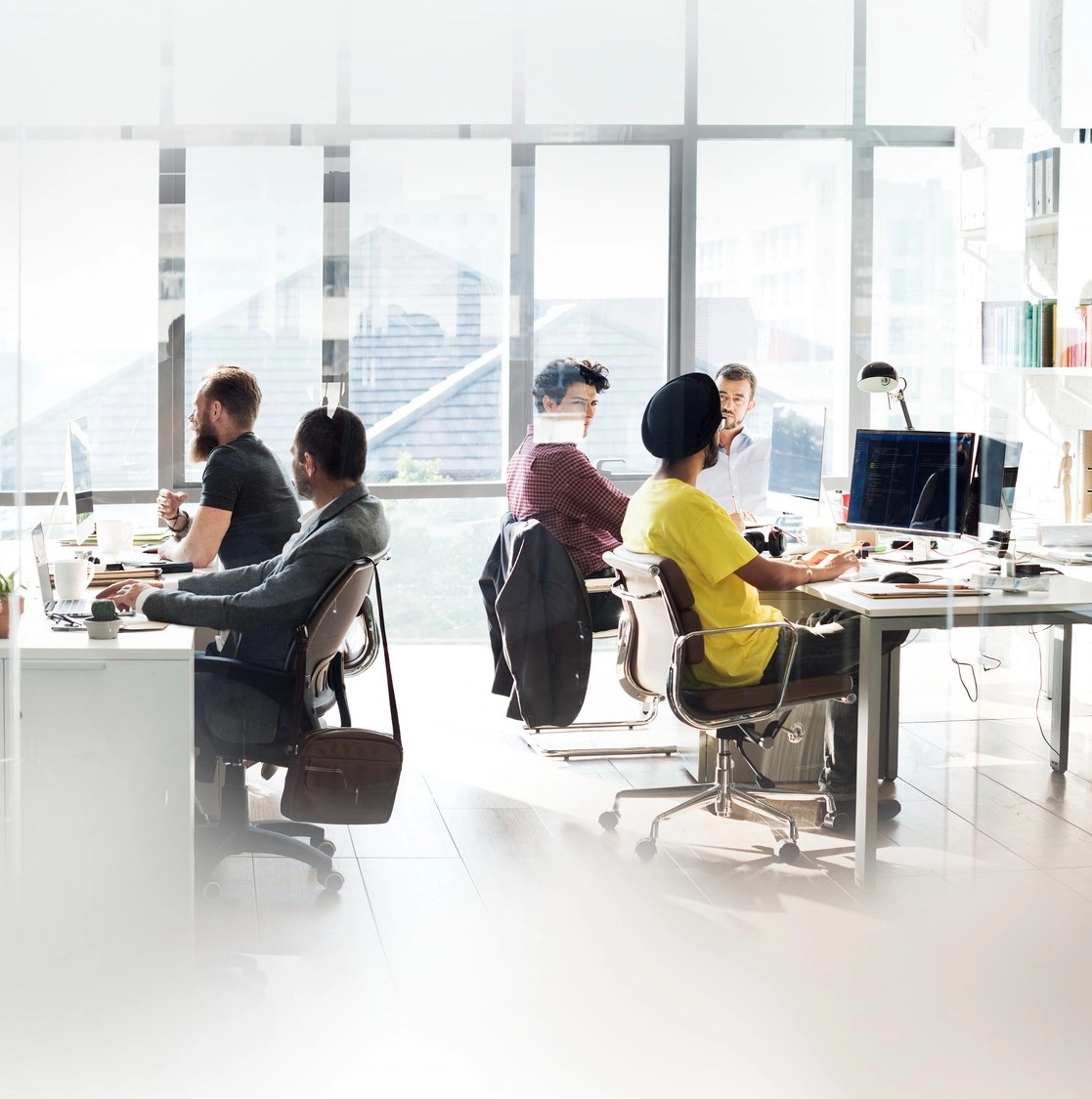 A software team at work in a bright open-plan office, with code on a monitor