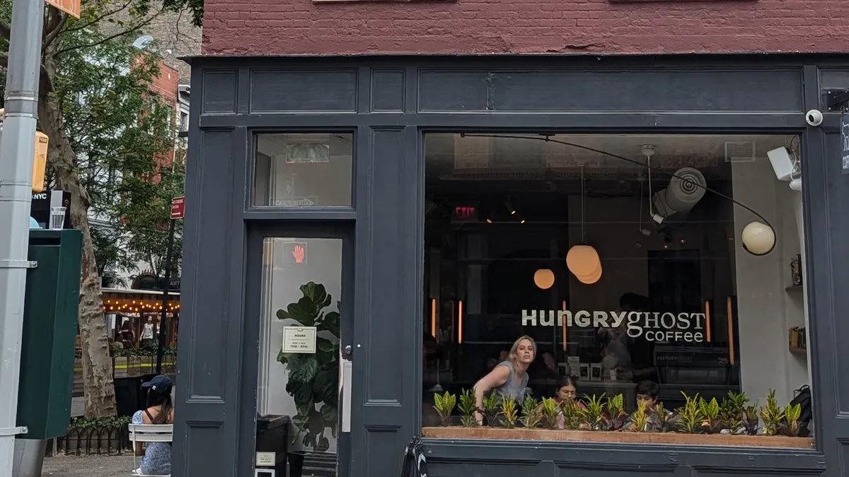 A view of a three-story brick building with a coffee shop on the first floor, with "Hungry Ghost Coffee" on the window.