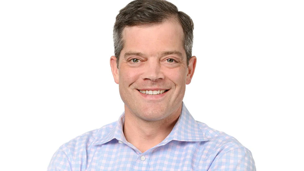 Portrait of a brown-haired man smiling at the camera.