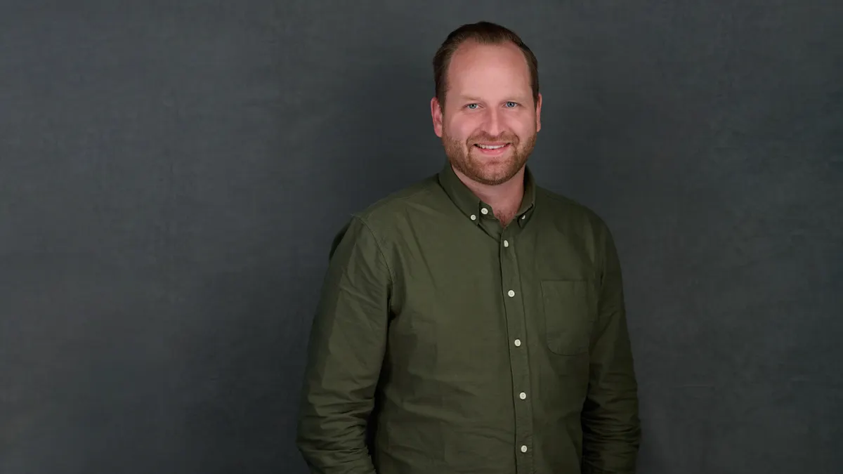 Portrait of a brown-haired man smiling at the camera.