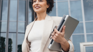 Woman standing in front of building holding a laptop
