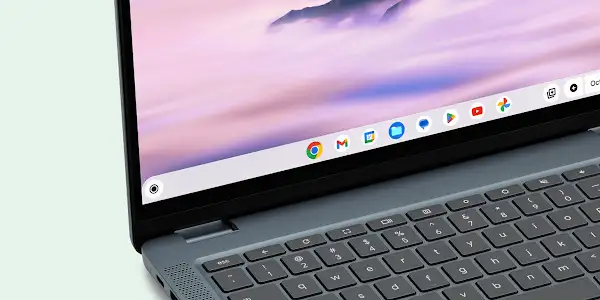 Close-up of a gray Chromebook laptop showing the keyboard and screen with app icons on the taskbar.