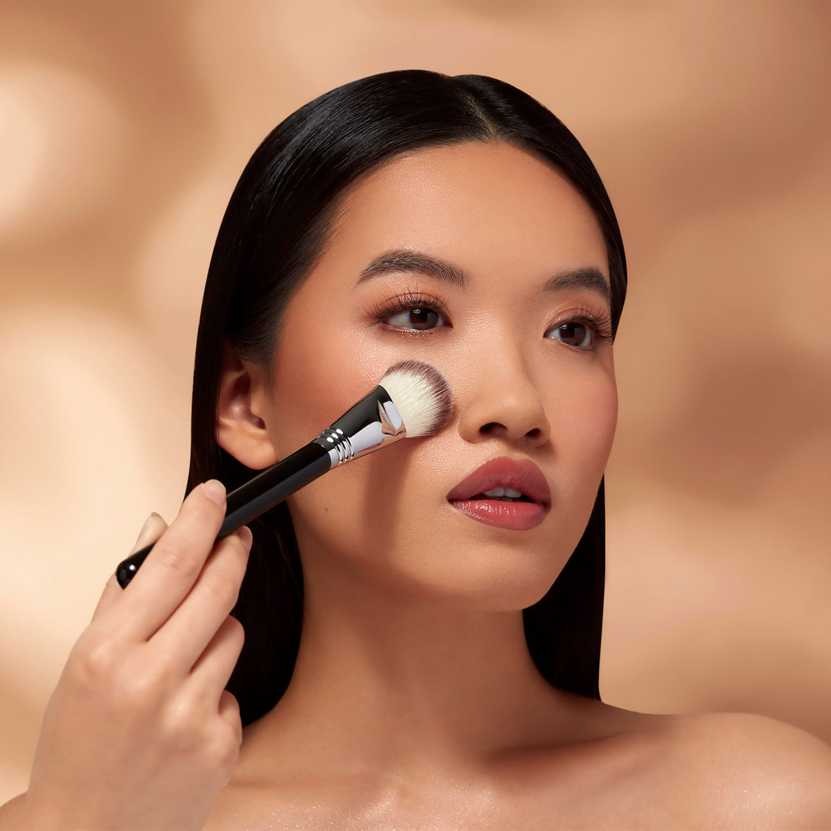 Woman acheiving Soft Coverage Makeup to her face with a Sigma Beauty Brush